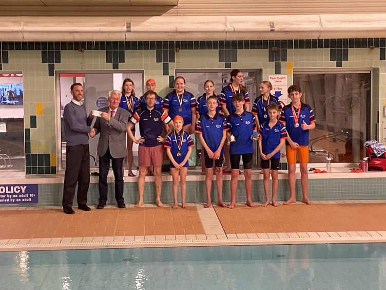 Jeremy Wilks, charity representative, from Kingsbridge Freemasons presenting the cheque to Dan, with the head coach of KKSC Conor Morgan flanked by some members of the swimming club.