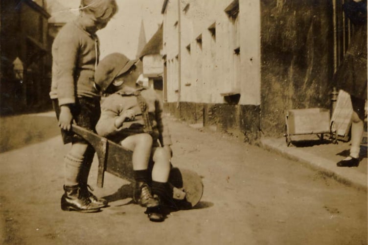 Scanned copy of a photograph of Malborough outside Callender’s Shop (1930s) Leslie Lapthorn (standing), Leslie Pepperell in barrow.