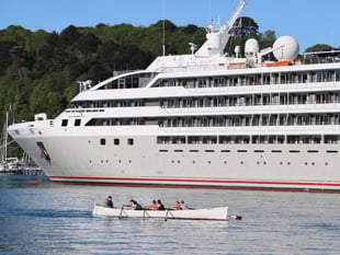 Rowers pass by 'Le Lyrial' cruise ship in the Dart 