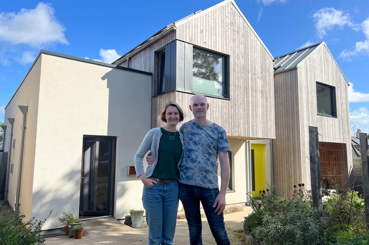A young couple in front of an eco-home