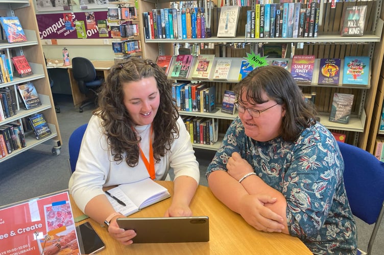 Digital Skills Devon: An individual receiving advice on how to use an iPad in a Devon library setting.
