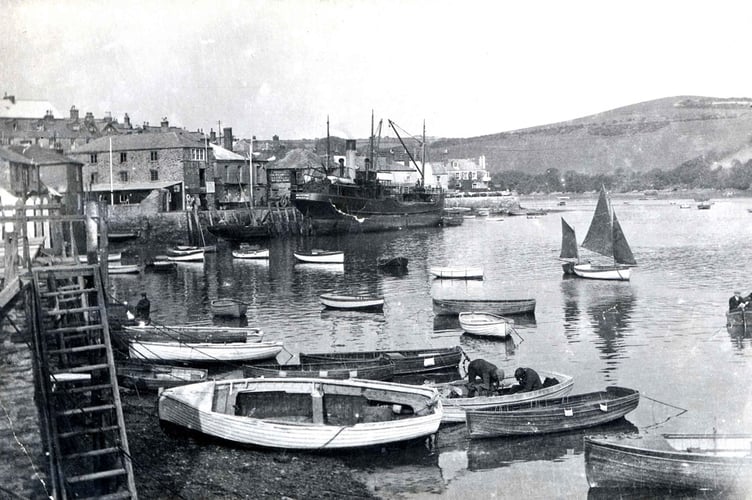 Boats in Salcombe. Small boats in foreground, larger boat moored at quayside in background.